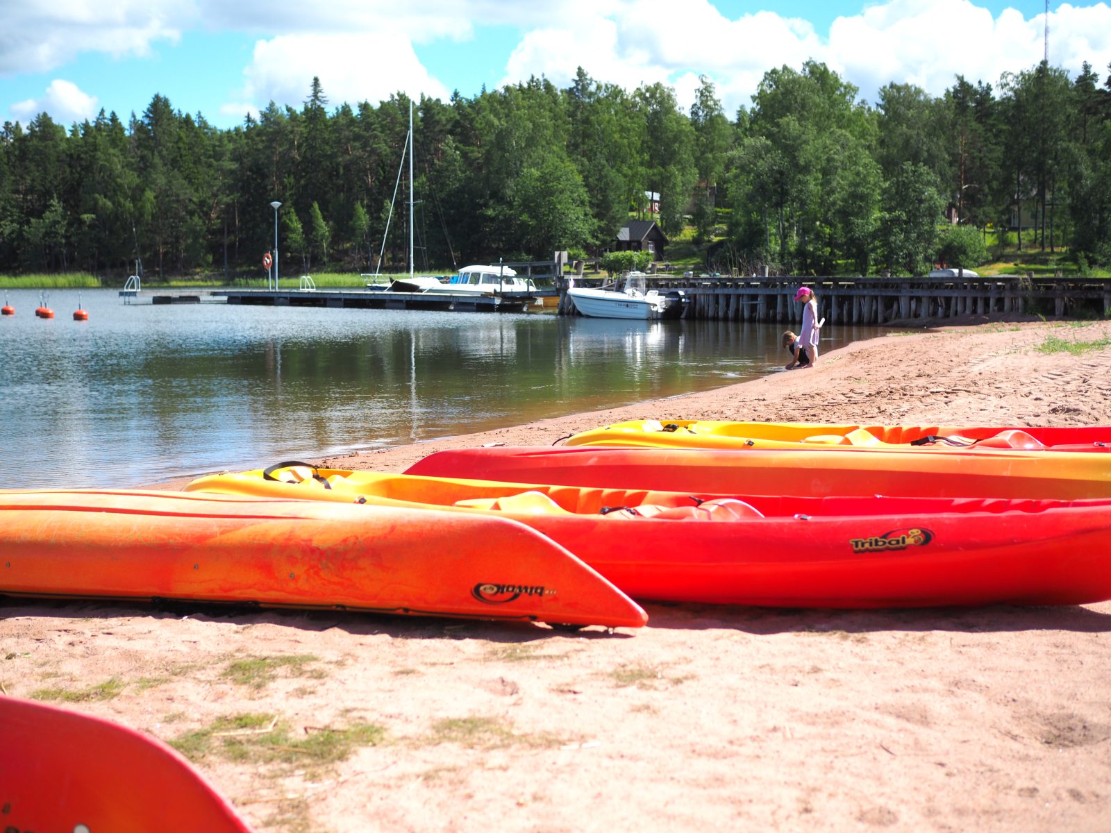 Värikkäät kanootit hiekkarannalla.