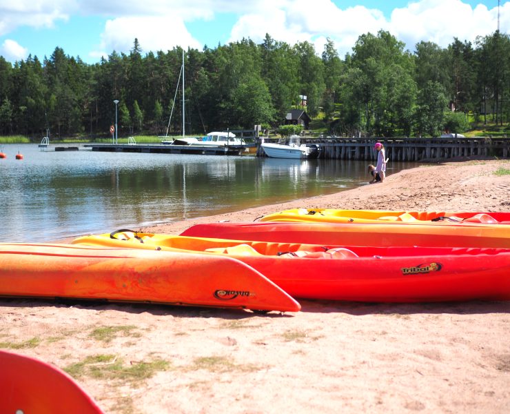 Värikkäät kanootit hiekkarannalla.