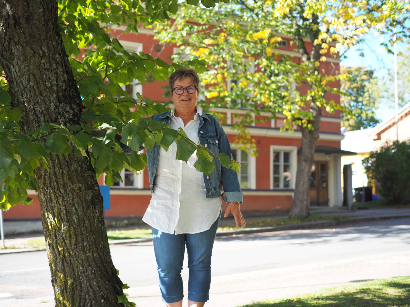 Teija Isotupa seisoo kirkkopuistossa, Raatihuone näkyy takana.